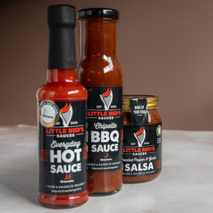 Lineup of Little Red's sauce collection with Everyday Hot Sauce in the forefront, followed by Chipotle BBQ, and Salsa at the back. This arrangement highlights the Everyday Hot Sauce's prominence while showcasing the diversity and depth of flavors available in Little Red's range, perfect for culinary explorations and flavor enthusiasts.