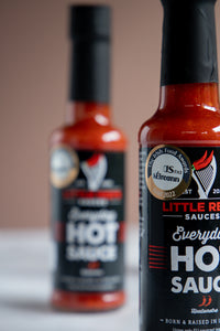Close-up of Little Red's Everyday Hot Sauce bottle, foregrounding the Gold Blas na hEireann Award sticker, with a second bottle subtly blurred in the background. This image highlights the prestigious award, showcasing the brand's commitment to quality and flavor in its acclaimed Irish hot sauce